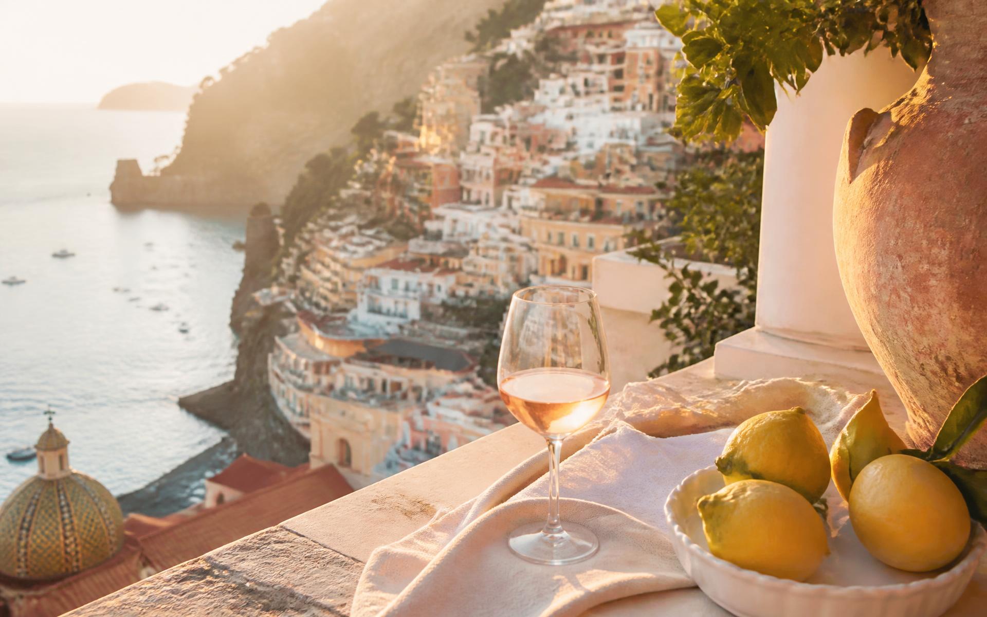 Wine glasses on a terrace above the Amalfi Coast at golden hour